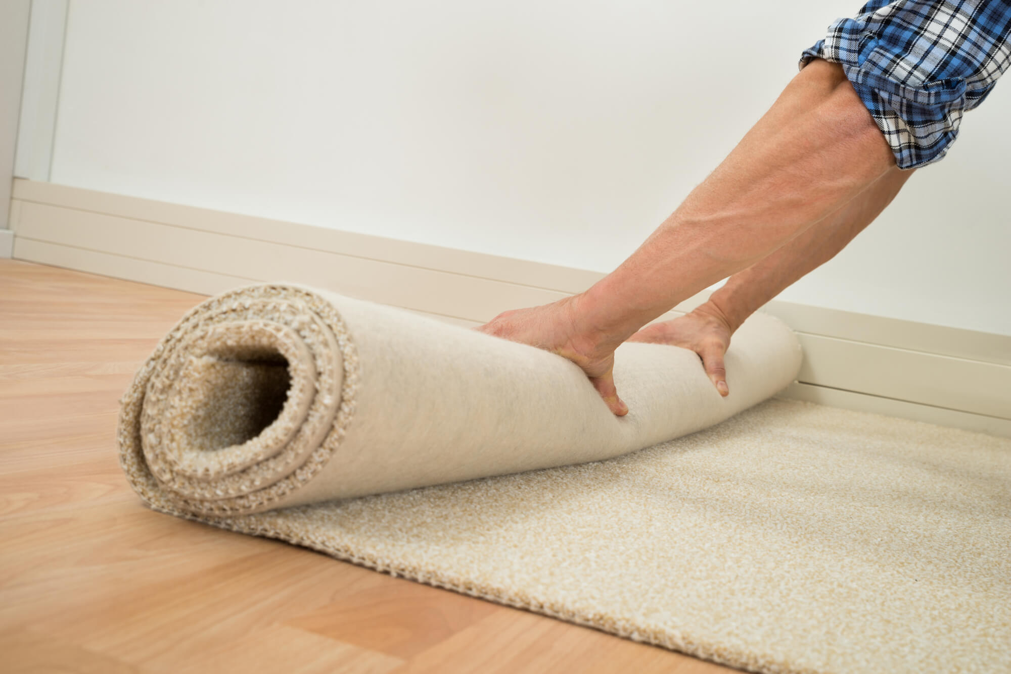 Man rolls up beige carpet